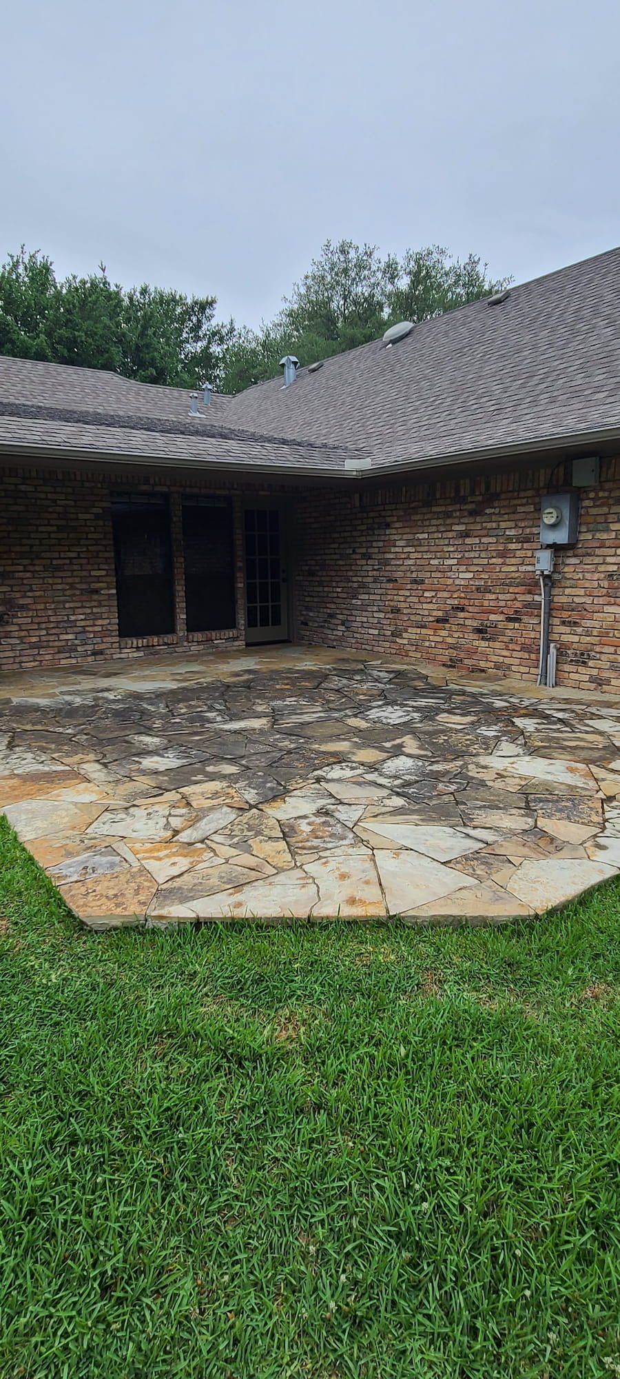 Dirty natural stone patio with heavy organic buildup before pressure washing in Corsicana Texas