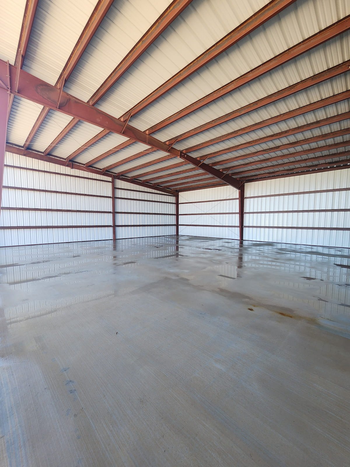 Construction cleanup in Purdon TX after pressure washing showing clean concrete floor inside metal building