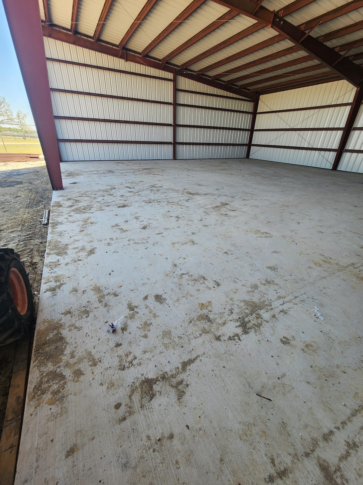 Construction cleanup in Purdon TX showing dirt, mud, and debris on new concrete floor before pressure washing