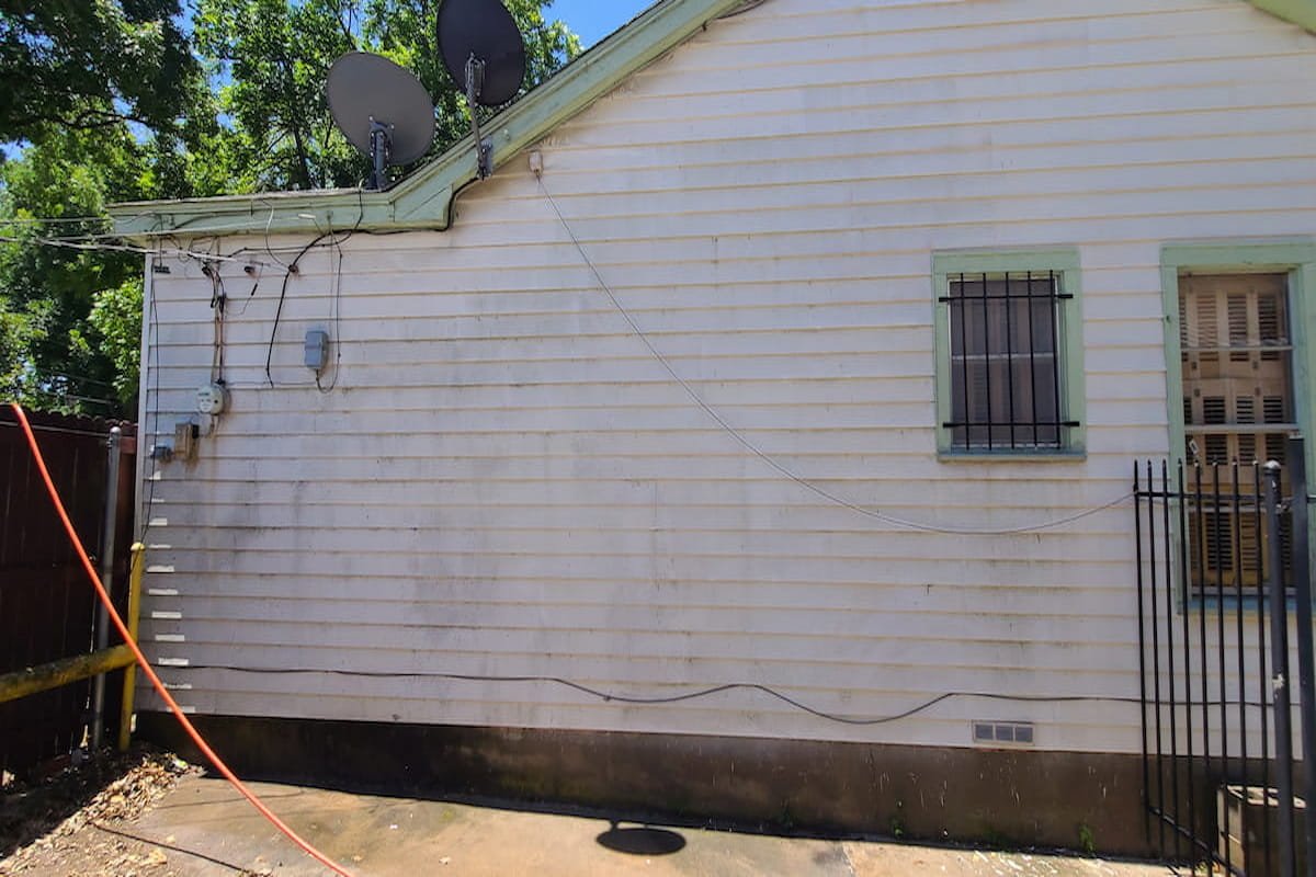 Dirty white vinyl siding with algae streaks before house washing in Corsicana Texas