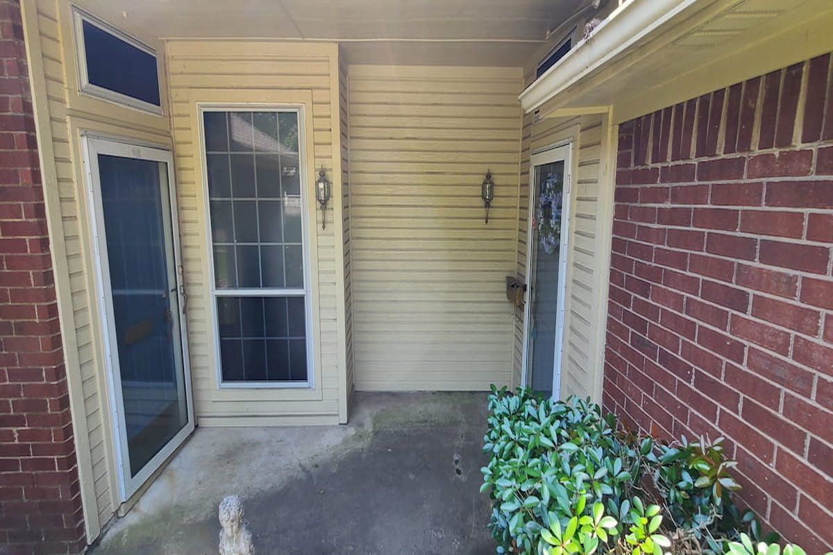 Dirty vinyl siding and entryway with algae and mildew buildup before house washing in Corsicana Texas Title