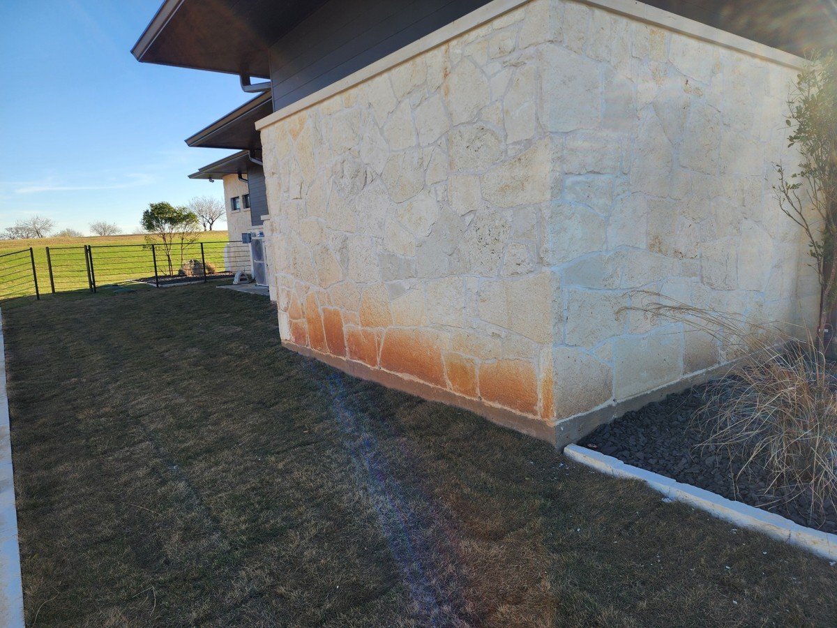 House exterior before washing in Streetman TX showing algae and red clay stains on limestone