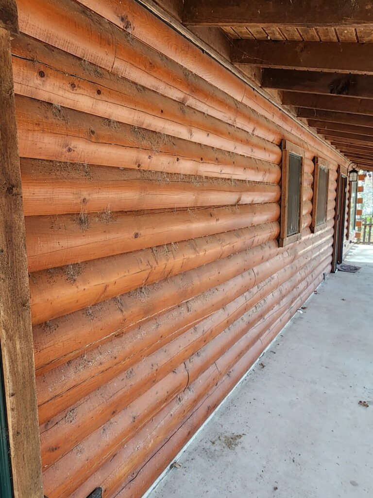 House washing before cleaning in Streetman TX showing dirt algae and spider webs on log siding exterior